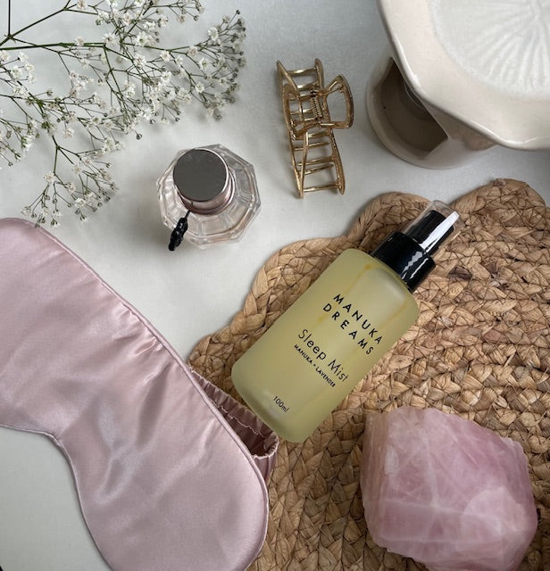 Manuka Dreams sleep mist bottle with flowers and pink eye mask on surface