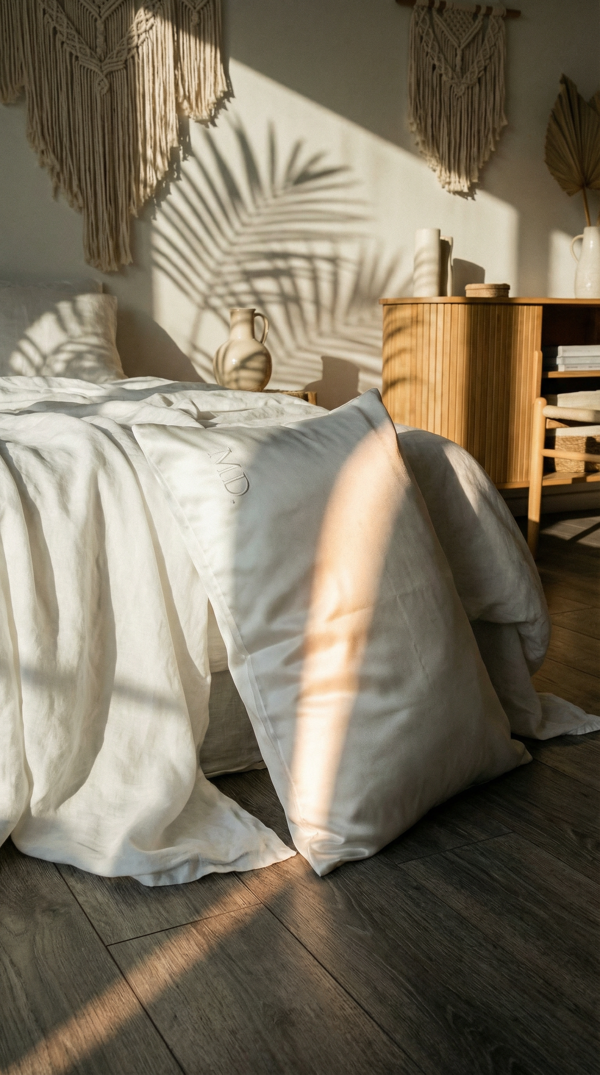 Sunlit bedroom with unmade bed palm shadows and warm wood furniture