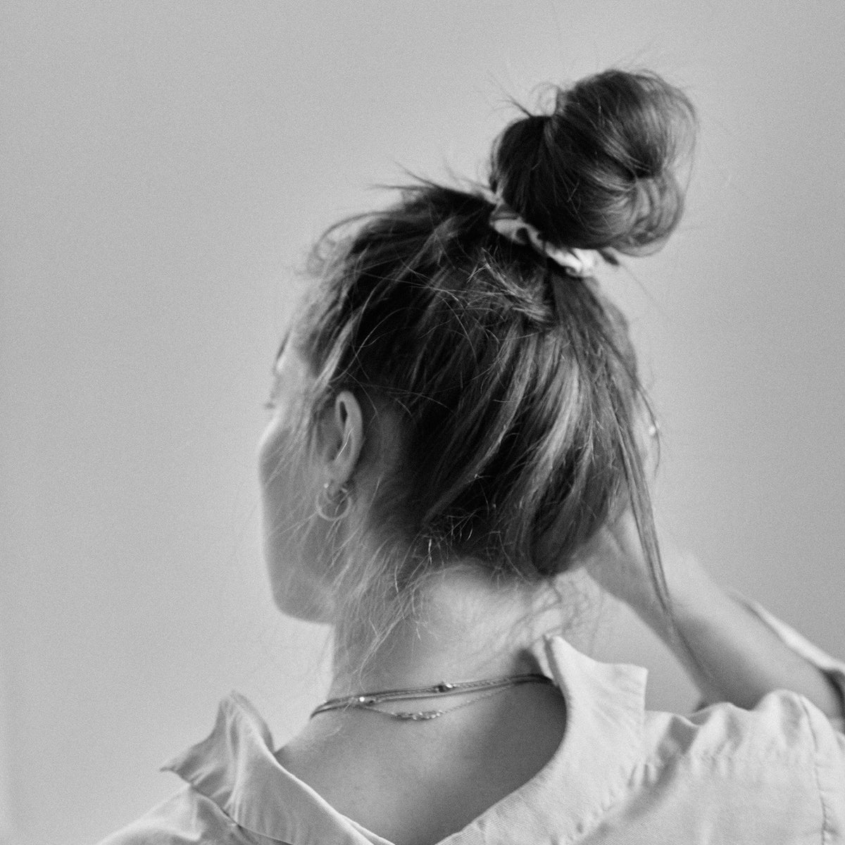 Woman from behind with messy bun and earrings in black and white